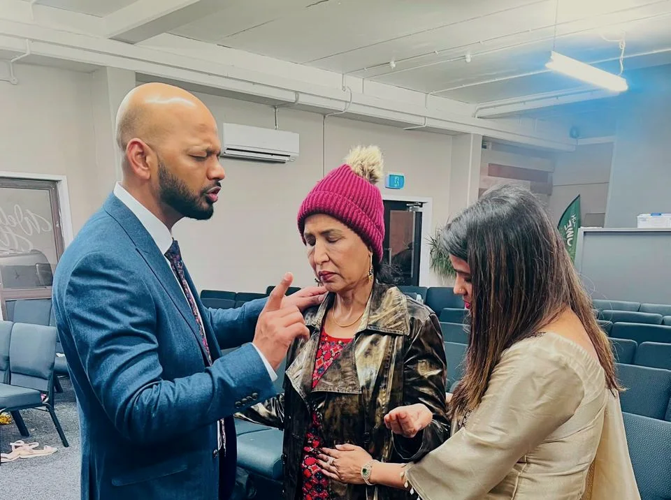 Pastor Vikas and Pastor Jyoti praying over a member of the congregation